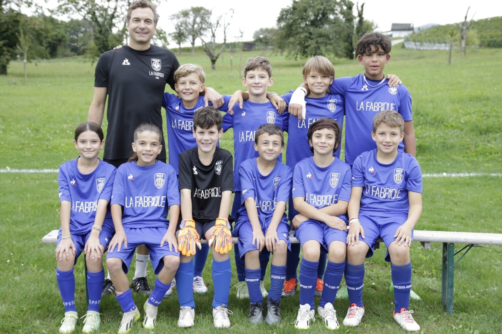 Youth soccer team and coach in uniforms posed on a field.