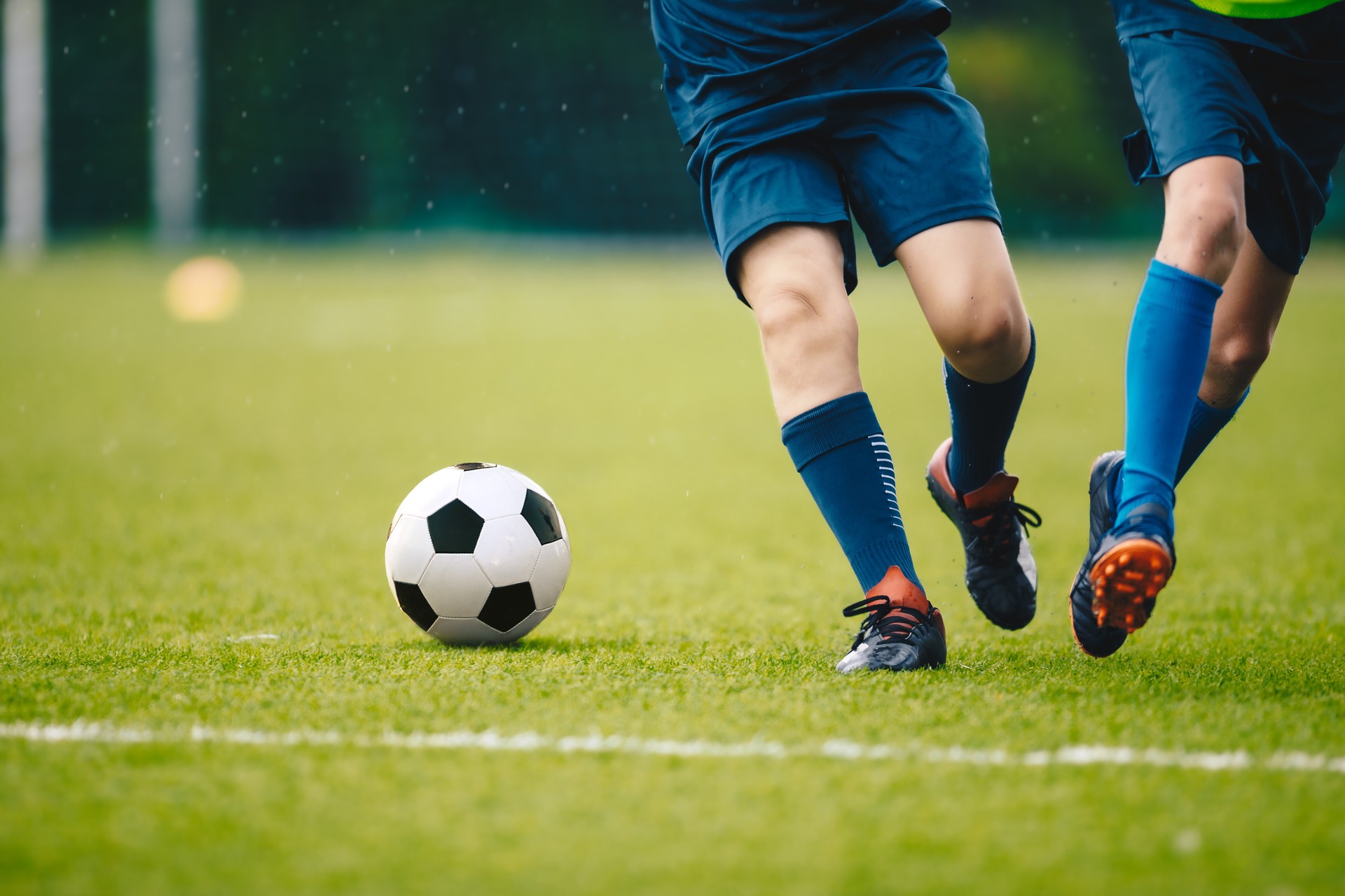 Deux joueurs de football adultes courant et tapant dans un ballon de football. Jambes de deux jeunes footballeurs lors d’un match. Les jambes des jeunes footballeurs européens en action